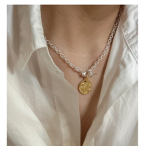 Detail of S925 silver two-tone necklace with hammered coin pendant and toggle clasp