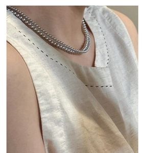 Gros plan sur un collier double rang en perles argentées porté par un mannequin