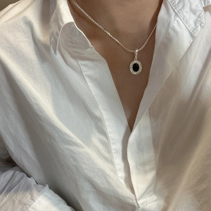 S925 sterling silver necklace with black onyx wavy pendant worn on a white shirt