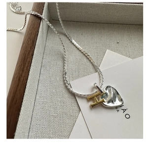 Close-up of S925 silver heart pendant with golden H charm and fine cable chain