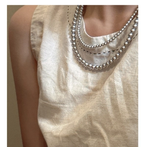 Détail d'un collier de perles argentées multicouches avec une finition métallique brillante
