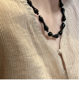 Detailed close-up of s925 silver beaded necklace with black teardrop agate on a model