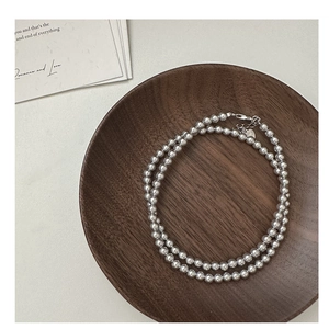 Détail du collier de perles grises avec pendentif coeur et fermoir sur bois