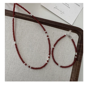 Detailed view of red agate beaded necklace and bracelet set with silver heart charm
