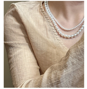 Primo piano di una collana di perle a doppio strato con perle di diverse dimensioni su una modella
