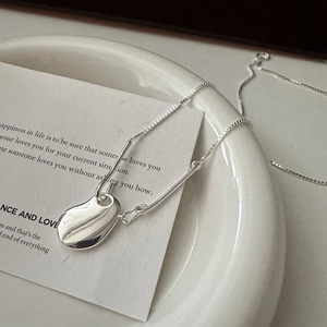 Minimalist S925 sterling silver necklace with irregular polished bean pendant on ceramic tray