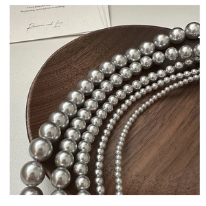 Gros plan de perles gris argent de tailles variées sur un plateau en bois