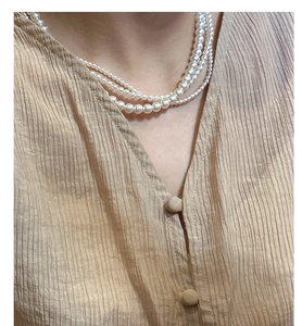 Détail d'un collier de perles multicouche en argent S925 montrant un éclat élégant