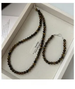 Detail shot of tiger eye stone bead necklace and bracelet set on an elegant cream tray