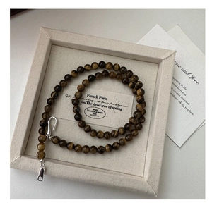 Detailed close-up of tiger eye stone beads necklace with silver clasp in a jewelry box