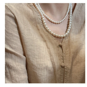 Gros plan d'un collier de perles double épaisseur en argent S925 sur chemise en soie