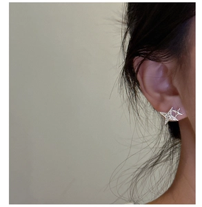 Close-up of S925 sterling silver star stud earrings with sparkling stones on a model's ear