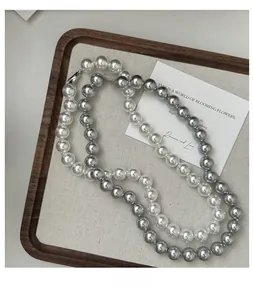 Detailed view of white and silver grey pearl necklaces on a rustic wooden tray