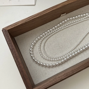 Elegante collana di perle a tre strati in argento S925 su vassoio di legno rustico