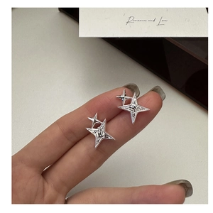 Macro shot of silver four-pointed star stud earrings with hammered metal texture details