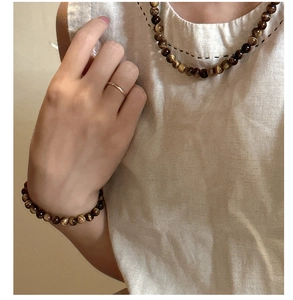 Detail of natural tiger eye bead necklace and bracelet set with golden ring on a model