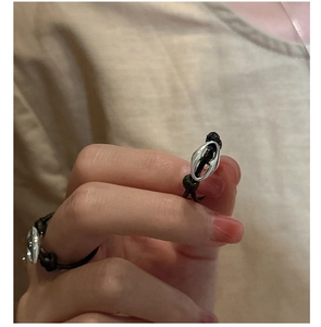 Detail of a black woven rope ring featuring a silver pig nose chain link design