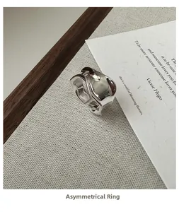 Dettaglio dell'anello d'argento ondulato con texture metallo liquido su tessuto