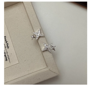 Macro detail of silver S925 four-point star earrings with unique hammered metal texture