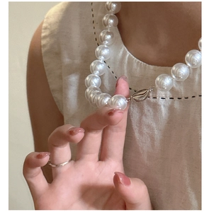 Close-up of a 12mm large white pearl necklace with silver clasp worn by a model