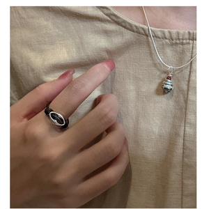 Close-up of S925 silver pig nose ring with black woven rope on finger and matching necklace
