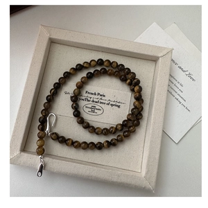 Close-up of S925 silver tiger eye stone beaded necklace on a beige jewelry display