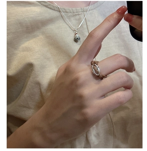 Detail of woven brown rope ring with silver oval centerpiece on model's finger
