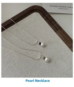 Gros plan du collier de perles en argent S925 sur un plateau à bijoux en bois texturé
