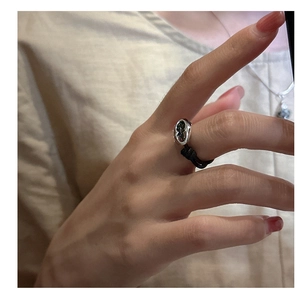 Detail of minimalist pig nose ring with black woven rope and silver oval metal piece