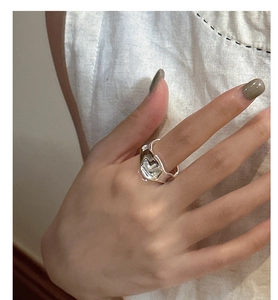 Vista macro di un anello ondulato in argento stile metallo liquido indossato da modella