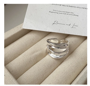 Detail of silver S925 tiered wave ring on a cream jewelry box with elegant artistic card