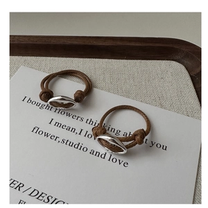 Detail of silver pig nose buckle ring and brown braided cord on aesthetic fabric