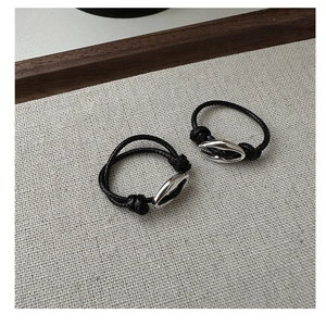 Close-up of minimalist black woven rings with polished silver metal oval accents