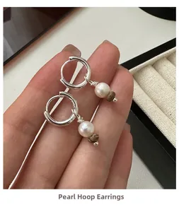 Détail de boucles d'oreilles créoles S925 avec perle blanche et perle en pierre brune