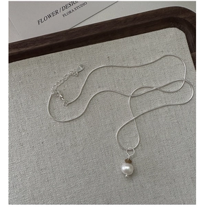 Gros plan d'un collier en argent S925 avec perle sur un plateau en bois