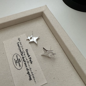 Elegant S925 sterling silver star stud earrings with double-layered design on beige display