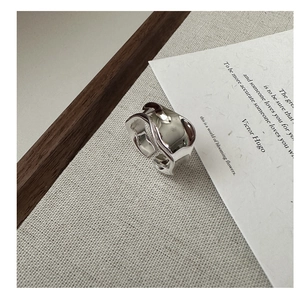 Anello in argento s925 con trama a onde e superficie irregolare su sfondo in tessuto