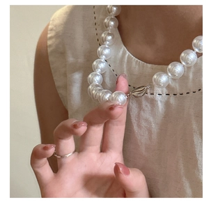 Detailed view of a S925 silver pearl necklace with a decorative shell clasp on a neck