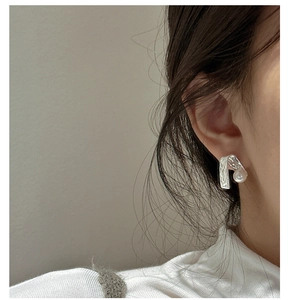 Detailansicht eines texturierten S925 Silberohrrings mit Perle am Ohr des Modells