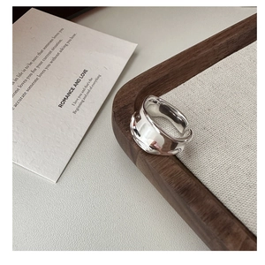 Dettaglio dell'anello d'argento a onde irregolari su un vassoio in legno chic