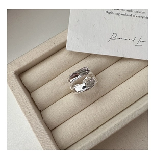 Detail of s925 silver double-layered liquid metal ring on beige velvet jewelry box