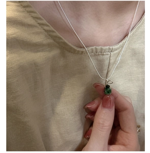 Detailed shot of a silver necklace featuring a square emerald green gemstone pendant