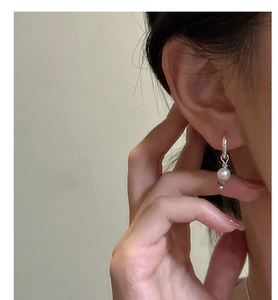 Détail d'une boucle d'oreille en argent S925 torsadé avec perle blanche sur l'oreille
