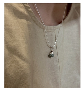 Détail macro du collier en argent S925 avec pendentif pierre verte enroulée sur un modèle