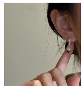 Gros plan d'une boucle d'oreille en argent S925 avec perle et fil torsadé sur l'oreille