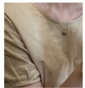 Gros plan du collier Saturne en argent S925 avec pendentif en pierre naturelle sur modèle