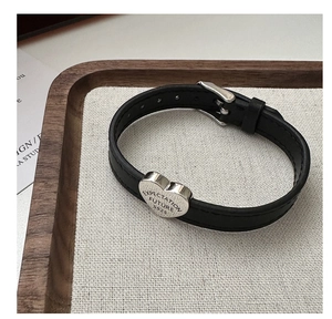 Detailed view of S925 silver heart charm with engraved text on a black leather strap