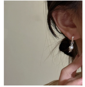 Détail de créoles en argent S925 avec perles blanches et grises portées par un mannequin