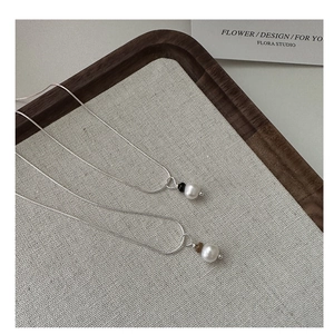 Détail de colliers en argent S925 avec perles sur un plateau de présentation tissé