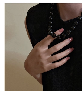 Detail of elegant black onyx bead necklace worn by a model in black sleeveless knitwear